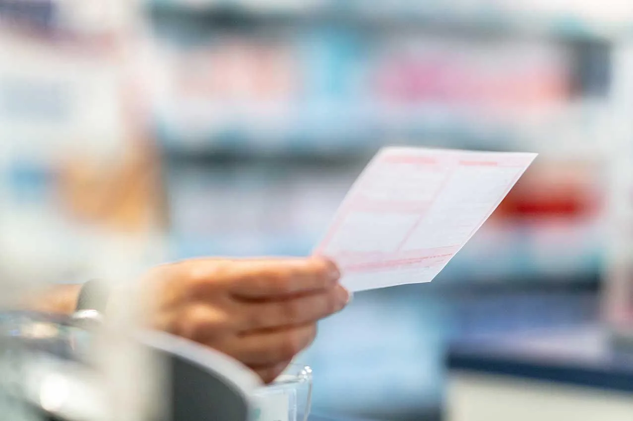 Die Hand eines Apothekers in der Apotheke hält ein Rezept