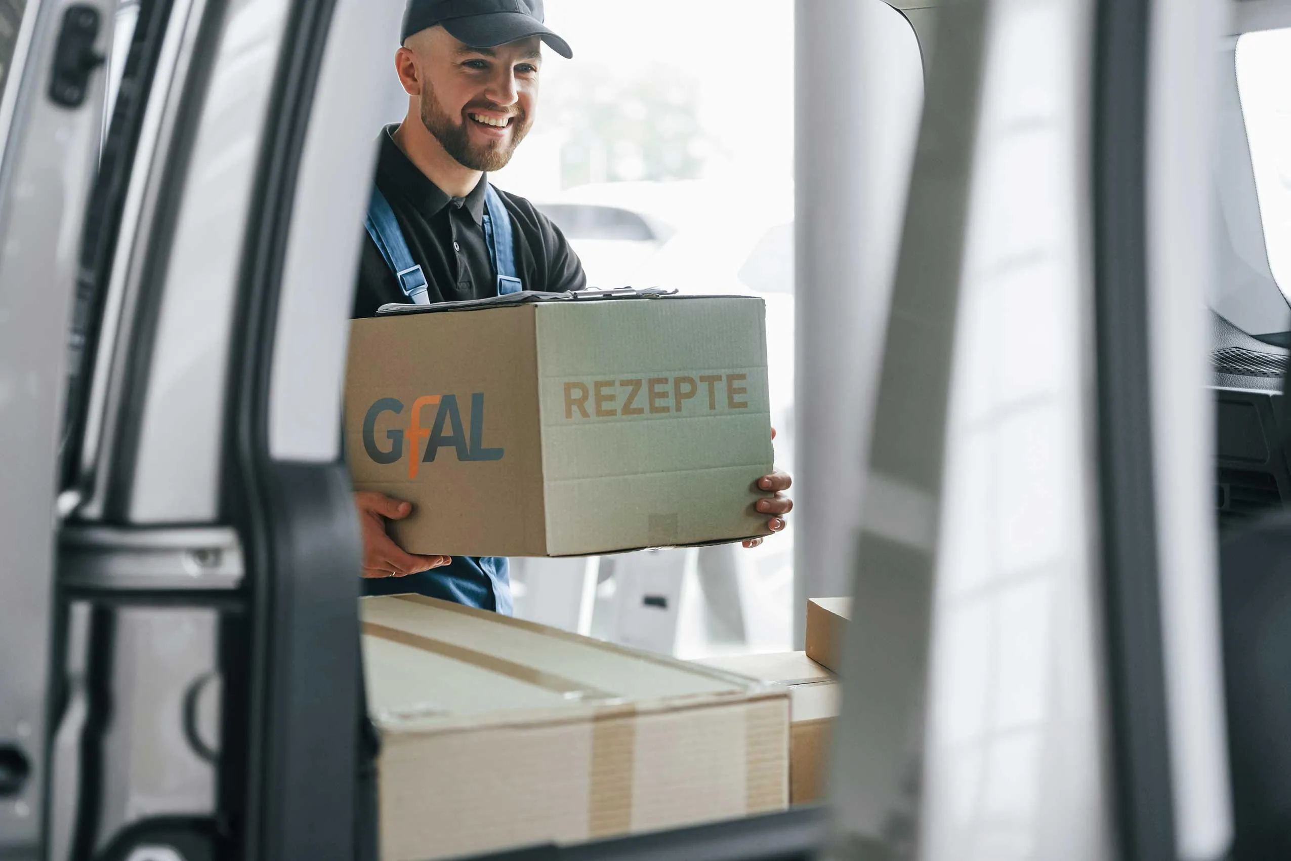 Ein Postbote holt ein Packet mit Rezepten für die GfAl aus ein Lieferwagen